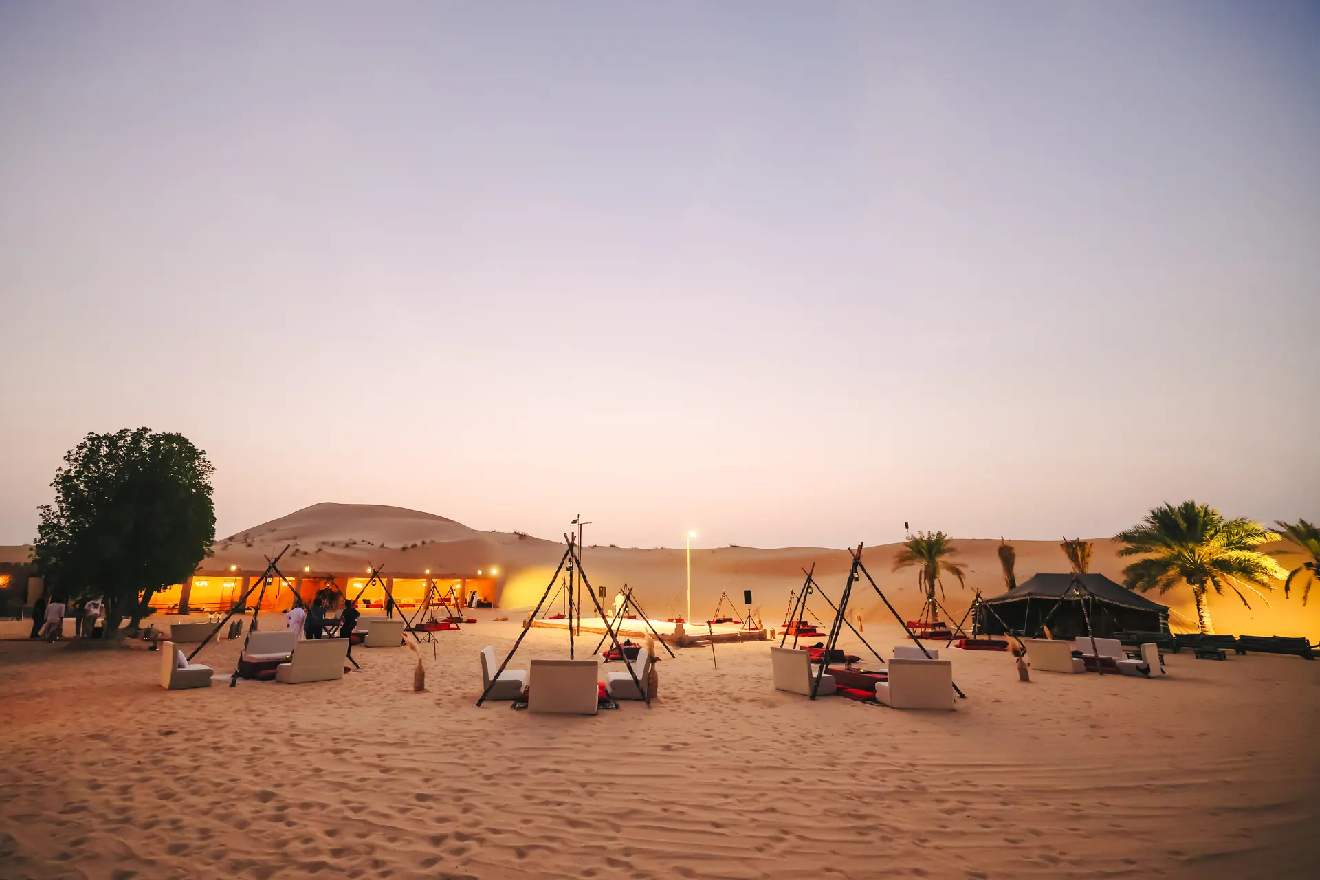 Khayal Al Sahra desert camp at dusk, lit majlis seating across the dunes at Al Khatim, Abu Dhabi