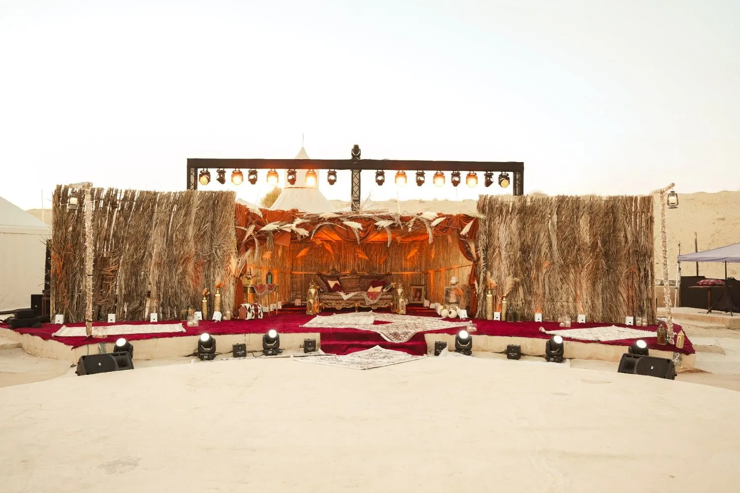 Desert wedding aisle with majlis seating, hand-tied florals and lantern path at Khayal Al Sahra Camp, Abu Dhabi